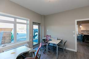 A room with a desk and chairs with a window overlooking a street.