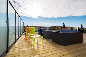 A balcony with a table and chairs overlooking the ocean.