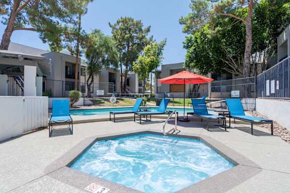 A pool with a hot tub and chairs in front of a building.