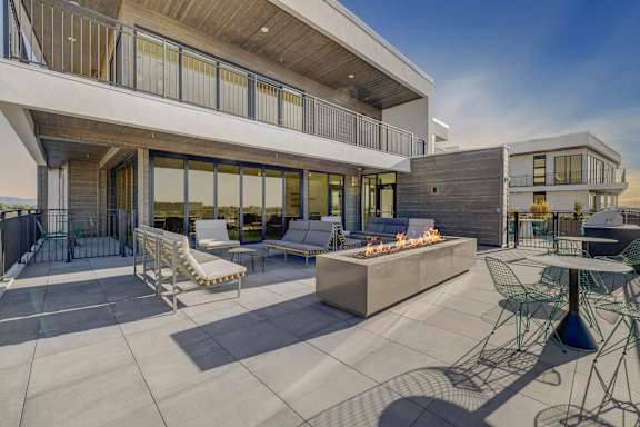 A modern patio with a fire pit and seating area.