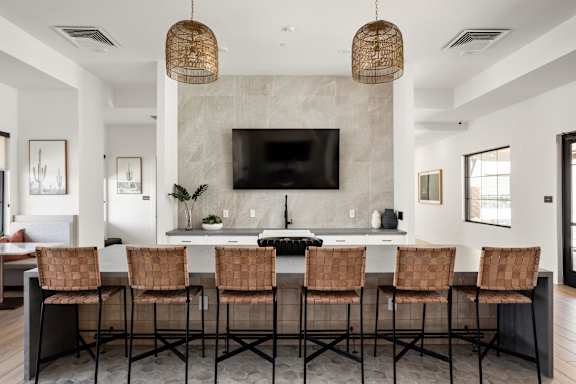 A modern kitchen with a bar area and chairs.