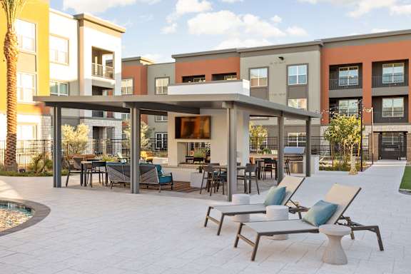 A patio with chairs and a table in front of apartment buildings.