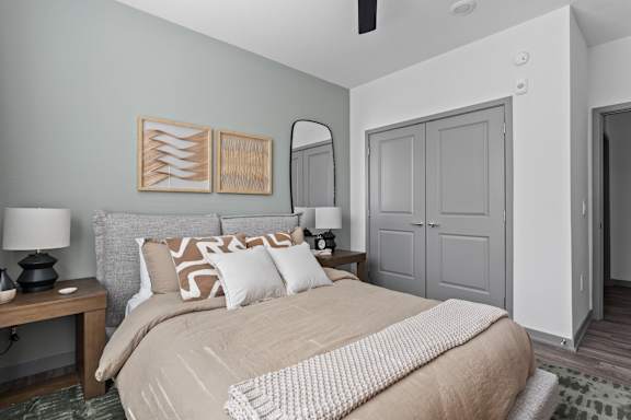 A bedroom with a bed, nightstand, and a painting on the wall.