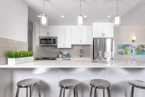 a kitchen with white cabinets and a counter top with three stools