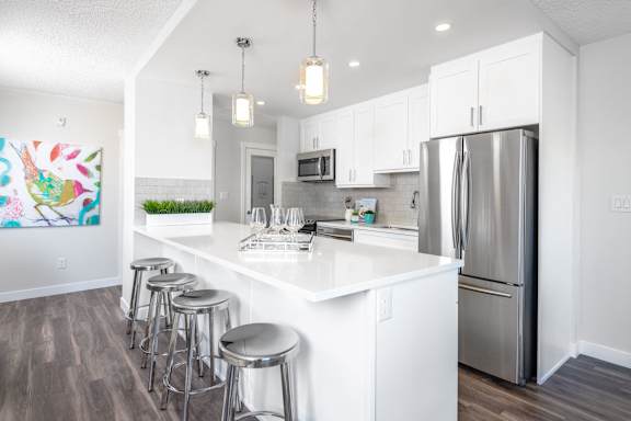 a white kitchen with stainless steel appliances and bar stools