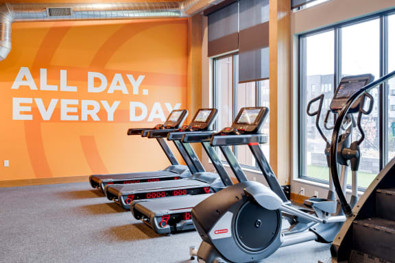 a row of treadmills in front of a wall with the words all day every day