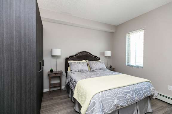 A bedroom with a large bed and a nightstand with a lamp.