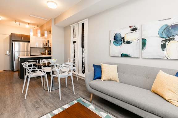 A modern living room with a grey couch and a dining table with chairs.