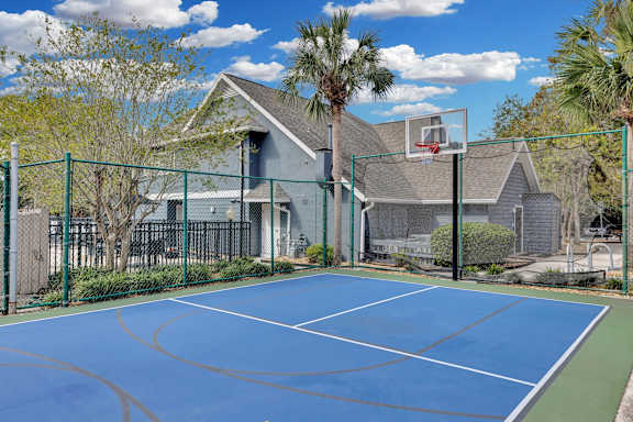 the backyard of a house with a tennis court and a basketball hoop