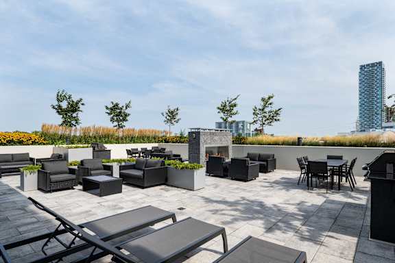 a rooftop patio with tables and chairs and a fire pit