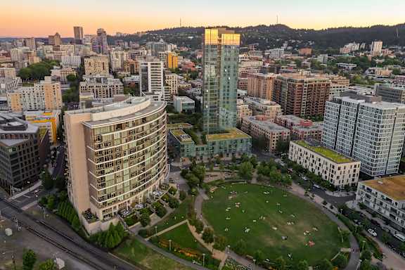 A cityscape with a large park in the foreground and buildings of various heights surrounding it.