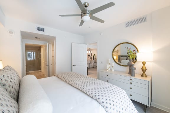 a bedroom with a large white bed and a white dresser with a mirror on it