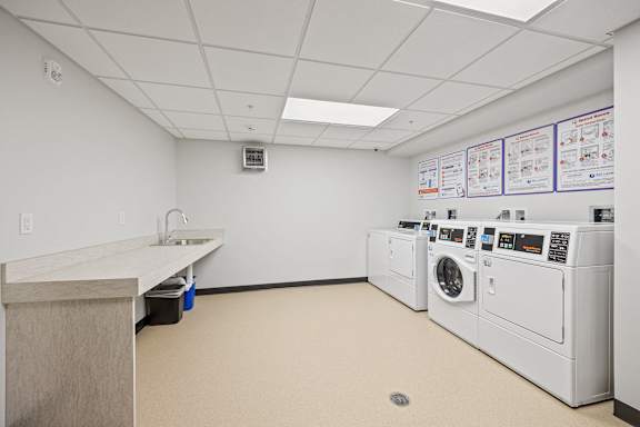 a laundry room with washes and dryers and a counter with a sink and