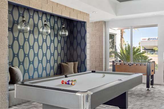 A pool table in a room with a blue patterned wallpaper.