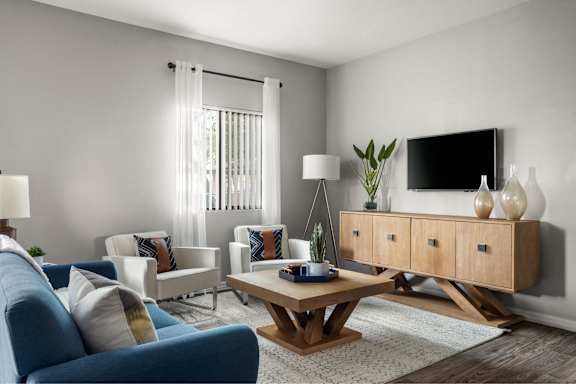 A living room with a blue sofa, a wooden coffee table, and a TV on a cabinet.