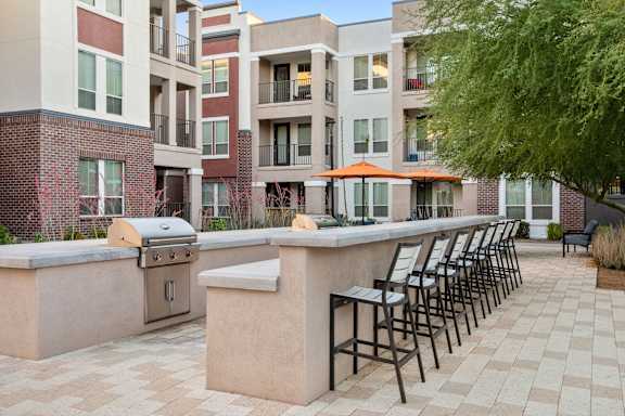 A patio with a bar and chairs is surrounded by apartment buildings.