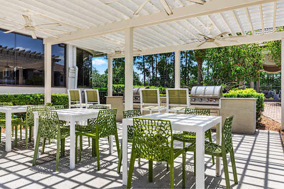 A white table and green chairs are set up under a white canopy.