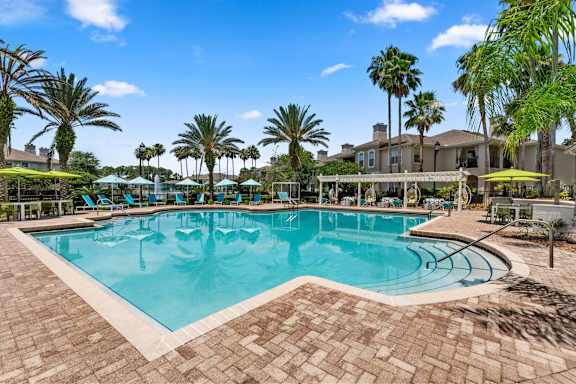 A large swimming pool surrounded by palm trees and lounge chairs.