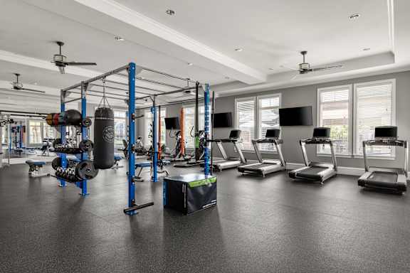 A gym with a variety of equipment including treadmills, weights, and a boxing ring.