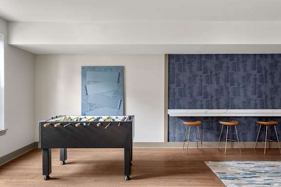 A pool table is in the middle of a room with a blue wallpapered wall and a blue rug on the floor.
