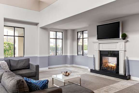 A living room with a grey couch, a white coffee table, and a fireplace.