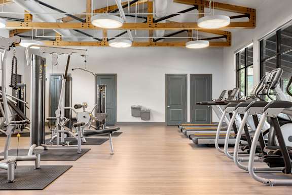 A gym with a variety of equipment including treadmills, weights, and exercise machines.