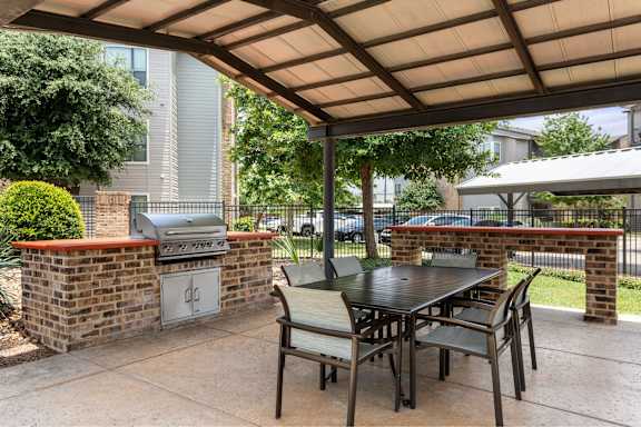 A patio with a table and chairs under a roof.