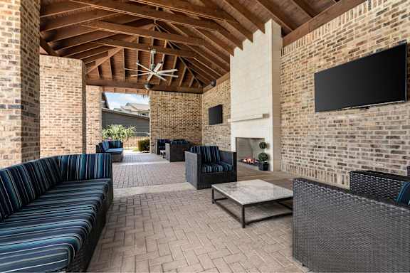 A patio with a black sofa and a TV mounted on the wall.