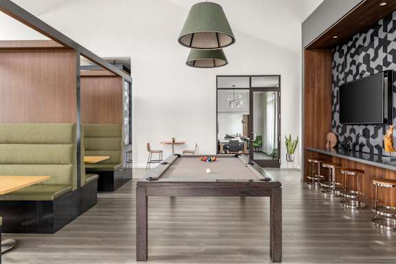 A room with a pool table and a bar area.