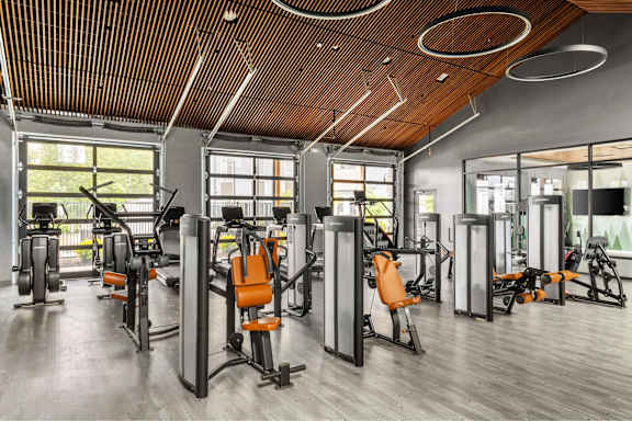 A gym with orange chairs and a wooden ceiling.