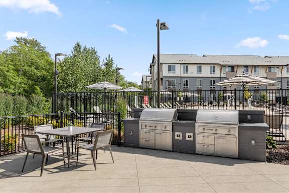 A patio with a table, chairs, and a trash can.