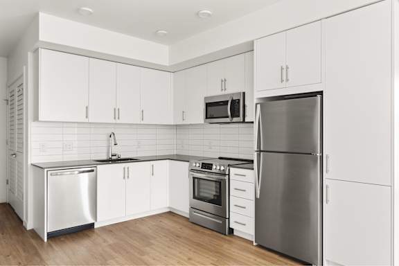 A modern kitchen with white cabinets and stainless steel appliances.