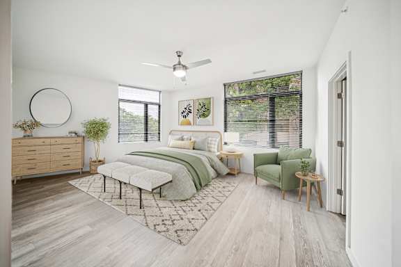 A bedroom with a bed, chair, and a plant.
