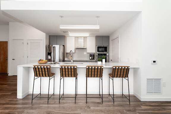 A modern kitchen with a white island and bar stools.