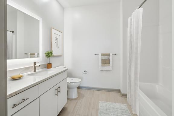 A white bathroom with a toilet, sink, and a plant.
