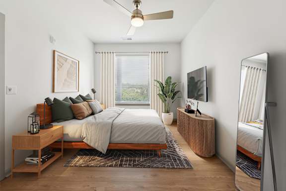 A bedroom with a bed, a nightstand, a plant, and a television.