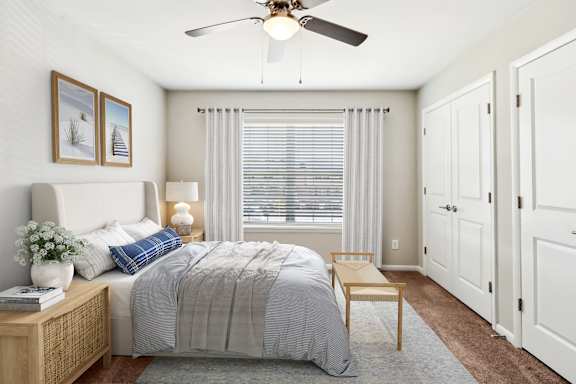 A bedroom with a bed, nightstand, and a ceiling fan.