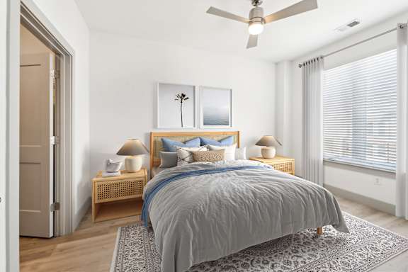 A bedroom with a bed, two lamps, and a ceiling fan.