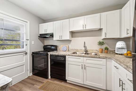 A kitchen with white cabinets and a black oven.