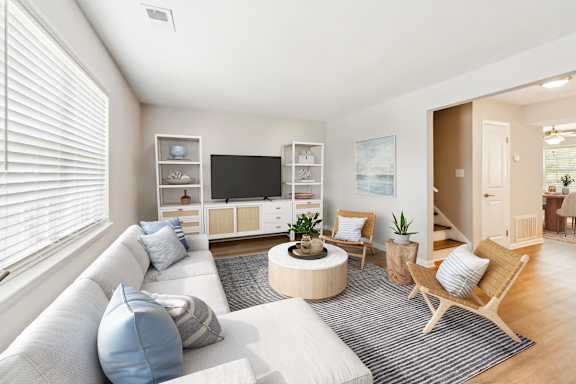 A living room with a white couch, a wooden coffee table, and a television.