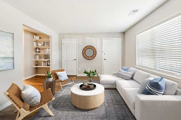 A living room with a white couch, a wooden coffee table, and a painting on the wall.