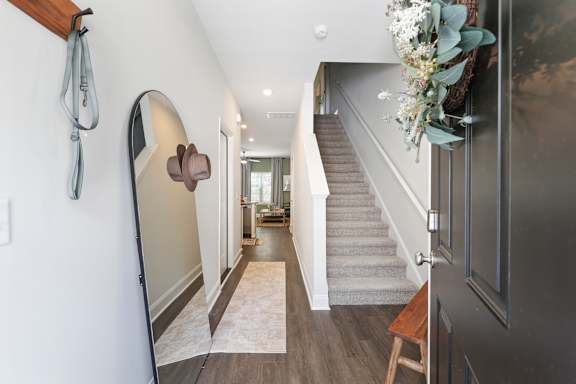 A hallway with a staircase and a mirror on the wall.