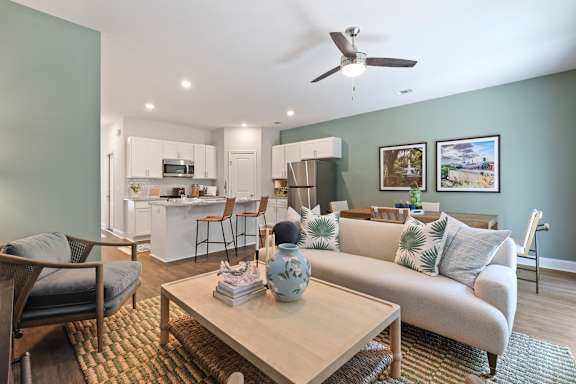 A living room with a grey couch, a coffee table, and a ceiling fan.