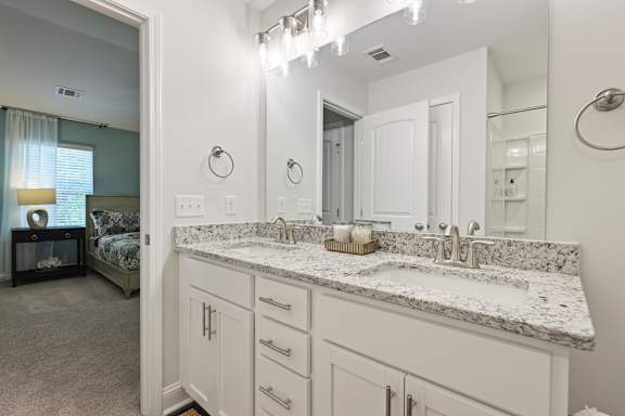 A bathroom with a marble countertop and white cabinets.
