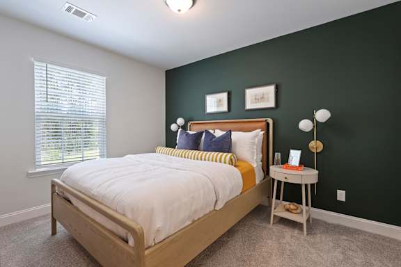 A bedroom with a bed, a nightstand, and a window.