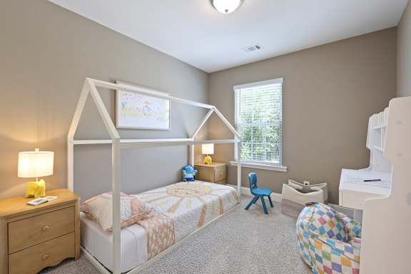 A child's bedroom with a bed, desk, chair, and a drawing on the wall.