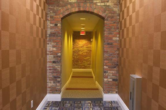 A hallway with a brick wall and a yellow door.
