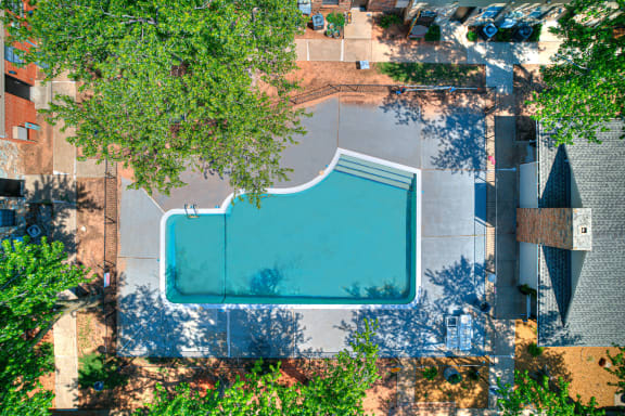 an aerial view of a swimming pool in the middle of some trees