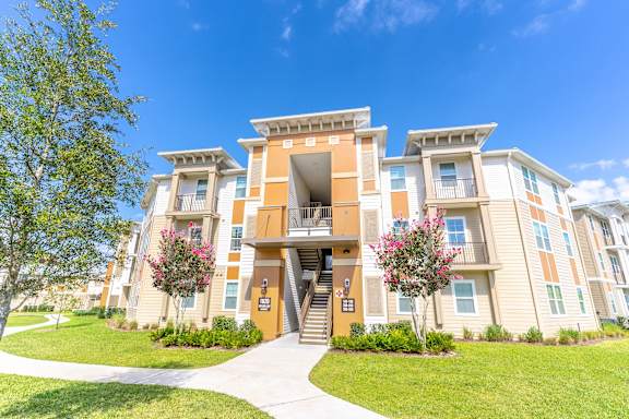 an exterior view of an apartment building with grass and trees