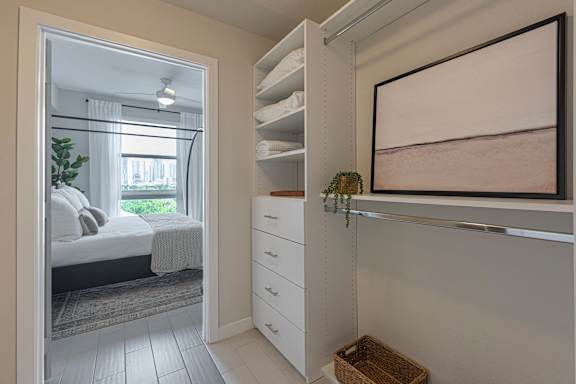 a walk in closet with a mirror and a bed in a room with